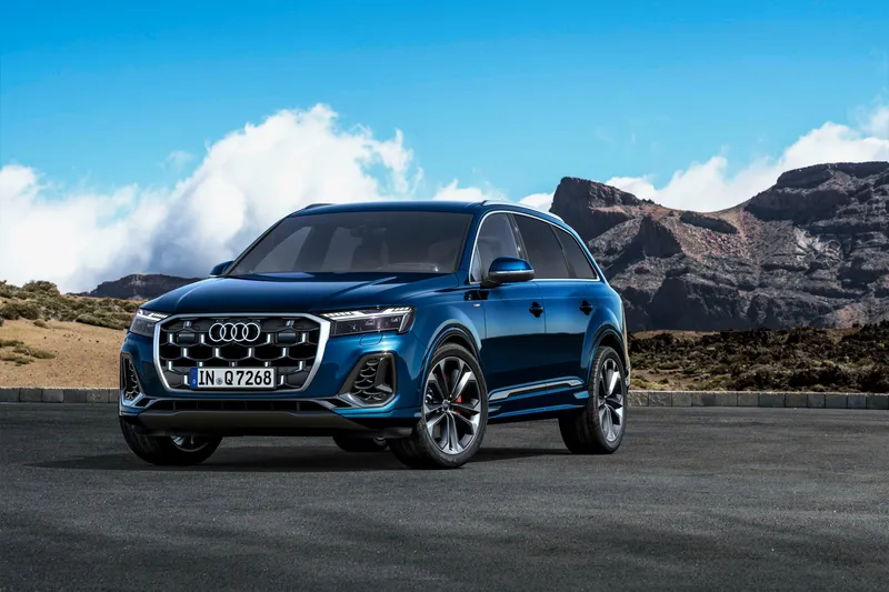 Audi Q7 azul SUV gran formato en perfil tres cuartos sobre fondo de cielo y montaña